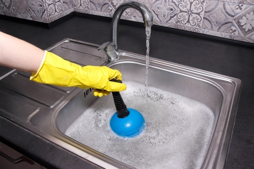 Plumber clearing a clogged drain pipe in a Riverbank, CA home